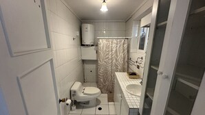 Un baño pequeño y funcional con inodoro, lavabo y ducha.