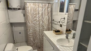 Un baño con inodoro, lavamanos y cortina de ducha.