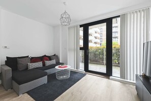 A modern living room with a sofa, a round coffee table, and a TV. - Modern 2 Bed 2 Bath with Patio | Close to Wembley (Greater London)