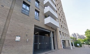 A multi-story building with a brick facade, a gated entrance, and a sign indicating parking conditions.