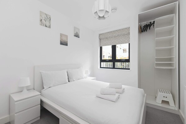 A white bedroom with a bed, nightstand, and a walk-in closet.