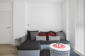A modern living room with a grey sofa, patterned pillows, a small side table, and a round coffee table with a tray. - Modern 2 Bed 2 Bath with Patio | Close to Wembley (Greater London)