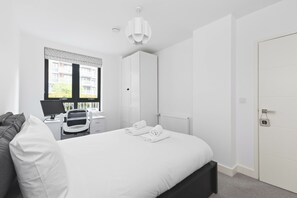 A modern bedroom with a bed, a desk, a chair, and a window. - Modern 2 Bed 2 Bath with Patio | Close to Wembley (Greater London)
