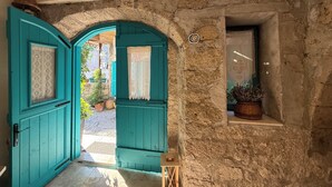 Μια αψιδωτή είσοδος με πόρτες σε τιρκουάζ χρώμα, που οδηγεί σε μια αυλή.