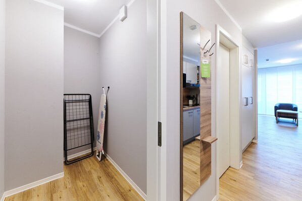 A hallway with a metal rack, a door leading to a kitchen, and a seating area with a sofa.