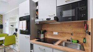 A modern kitchen with a built-in oven, microwave, and stainless steel sink. - ADAPT APARTMENT HOTEL Wetzlar (Wetzlar)