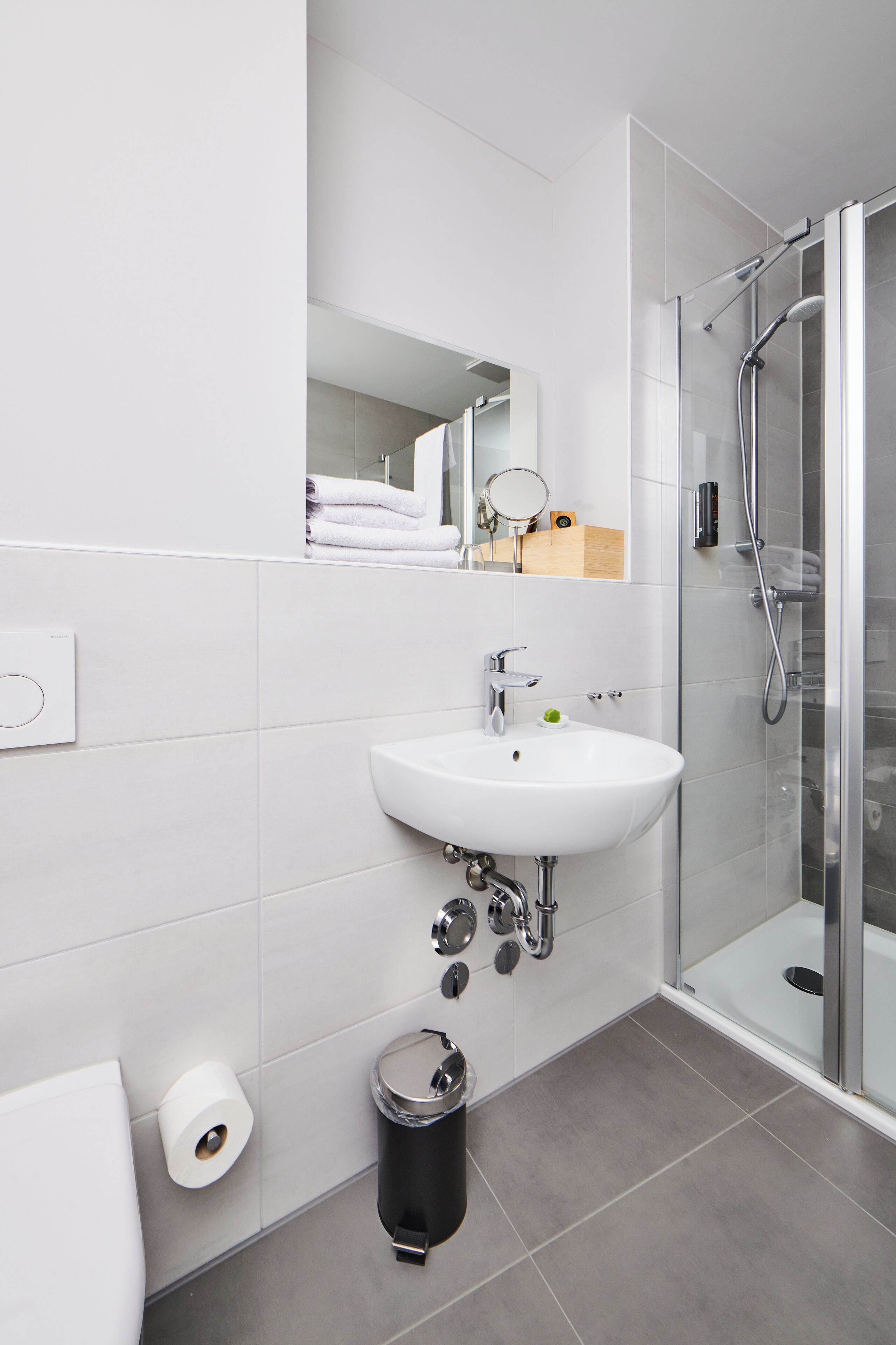 A modern bathroom with a white sink, a glass shower enclosure, and a mirror above the sink.