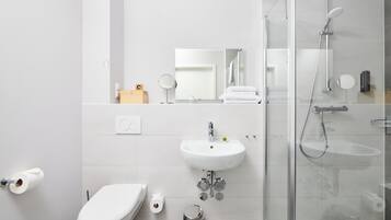 A modern bathroom with a toilet, sink, and glass-enclosed shower.