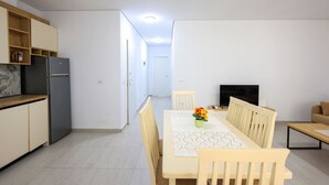 A modern kitchen with a refrigerator, wooden cabinets, and a dining area with a table and chairs.