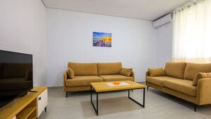 A modern living room with two sofas, a wooden coffee table, and a flat-screen TV.