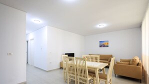 A modern living room with a dining area, a sofa, and a TV.