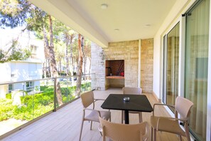 A balcony with a stone wall, a table, and chairs. - Sanpietro Vacation Apartment 042 (Ishëm)