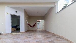 A hallway with a hammock, a door leading to another room, and a tiled floor. - Casa em Peruíbe a 250m da Praia com Piscina (Peruíbe)