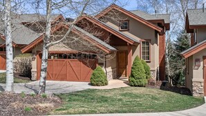 A two-story house with a brown garage, a covered driveway, and a well-maintained lawn. - Midway 4 Bedroom Golf Course Luxury Turnberry 23 Home (Midway)