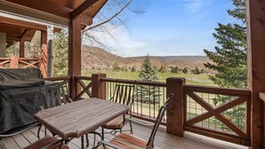A wooden deck with a table and chairs, overlooking a scenic landscape with hills and trees. - Midway 4 Bedroom Golf Course Luxury Turnberry 23 Home (Midway)
