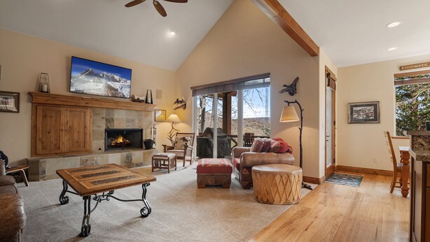 A spacious living room with a fireplace, wooden furniture, and a large window offering a view of the outdoors. - Midway 4 Bedroom Golf Course Luxury Turnberry 23 Home (Midway)