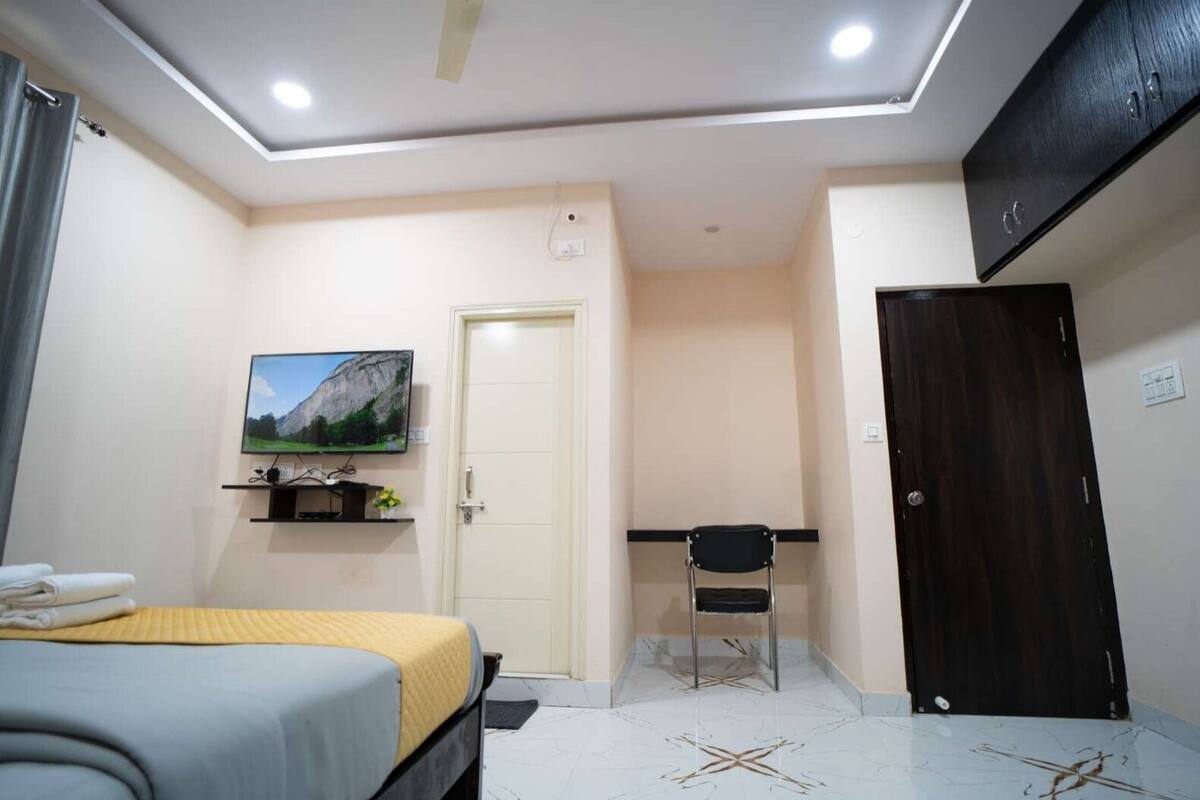 Une chambre d’hôtel comprenant un lit, un bureau avec une chaise, un téléviseur fixé au mur et une armoire.