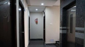 Un pasillo moderno con piso negro pulido, un extintor de incendios montado en la pared y una puerta a la izquierda.
