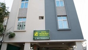 Un hotel de varios pisos con un cartel que dice 'Hotel Yellow Bells Qachiqui' y un número de contacto.