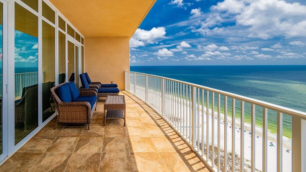 Ein Balkon mit Korbmöbeln, Blick auf das Meer und einem weißen Geländer.