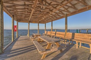 A wooden deck with benches and picnic tables overlooking a body of water.