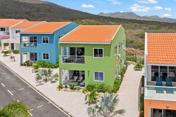 A row of modern, two-story buildings with orange tiled roofs, surrounded by greenery and a clear sky. - Bon Azul 5A Ocean Resort (Sabana Westpunt)