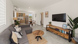 Una sala de estar moderna con un sofá gris, una mesa de centro de madera y un televisor en la pared.
