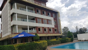 Un hôtel à plusieurs étages doté d’une piscine, de balcons et de parasols à l’effigie de Pepsi.
