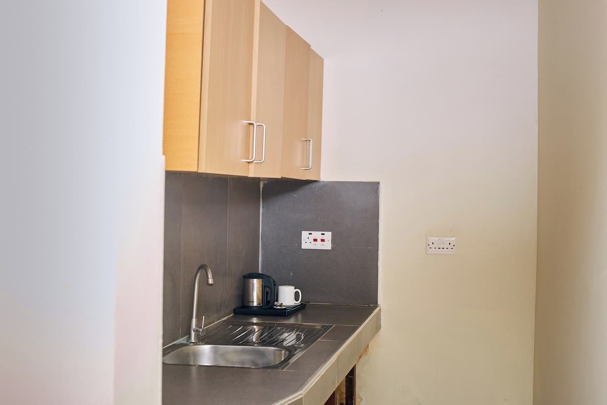 A compact kitchen with a stainless steel sink, a coffee maker, and wooden cabinets.