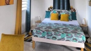 Une chambre à coucher avec un lit, des oreillers, une chaise, une fenêtre et un tableau au mur.