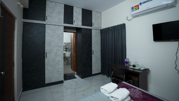 A hotel room with a bed, a desk, a TV, and a wardrobe.