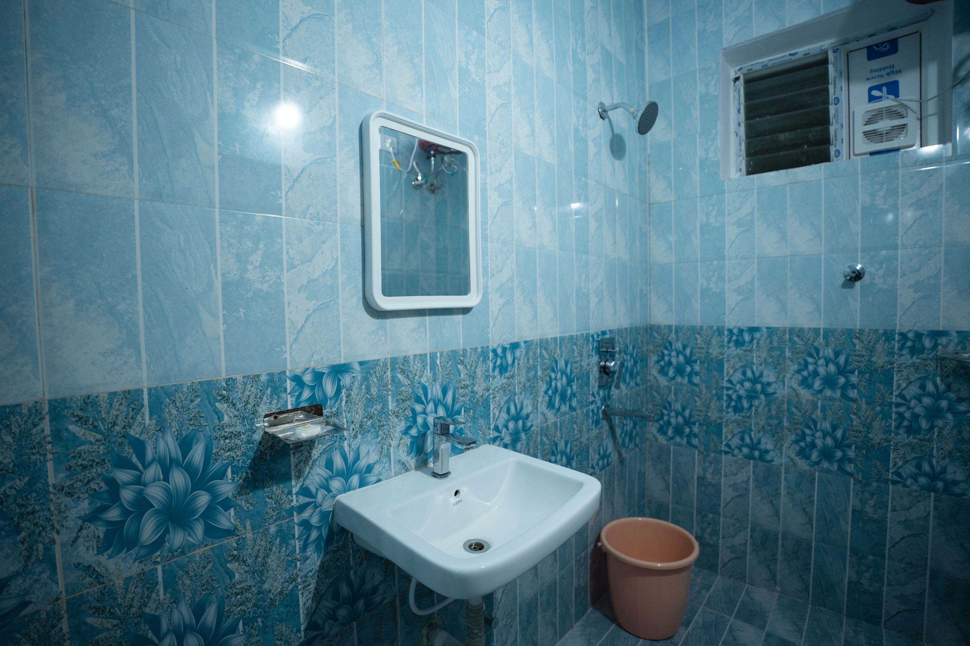 Een badkamer met een witte wastafel, een spiegel en een douchekop.