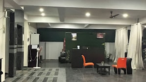 A spacious indoor area with a reception desk, seating arrangements, and a ceiling fan.