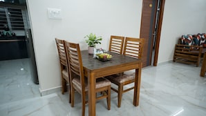 A dining area with a wooden table and chairs, a potted plant, and a fruit bowl.