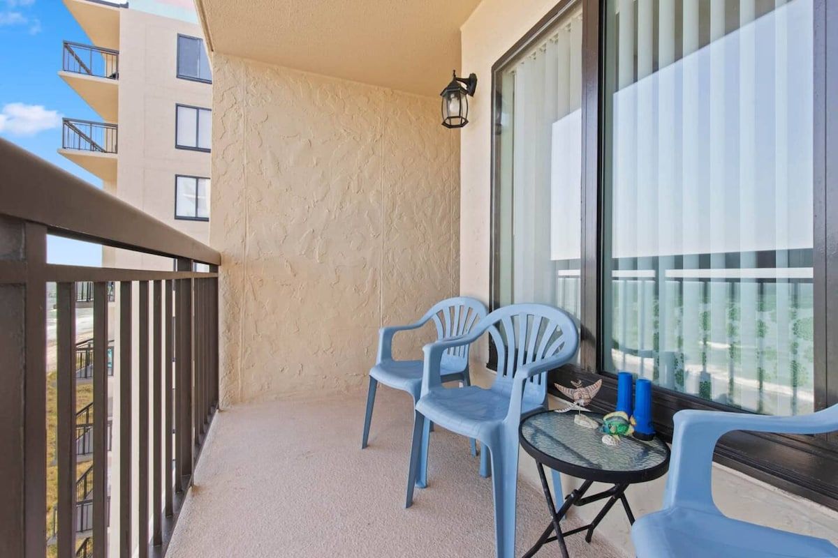 A balcony with two chairs, a small table, and a potted plant.