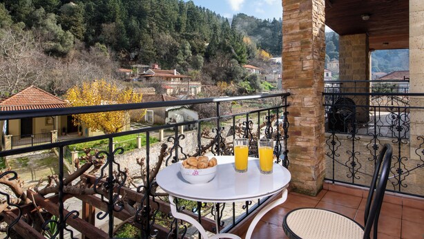 Un balcón con una mesa dispuesta para el desayuno, con vistas a un paisaje montañoso.