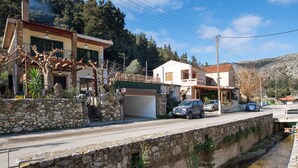 Un canal bordeado de piedra con un muro de piedra a un lado y una calle con coches aparcados y edificios al otro.