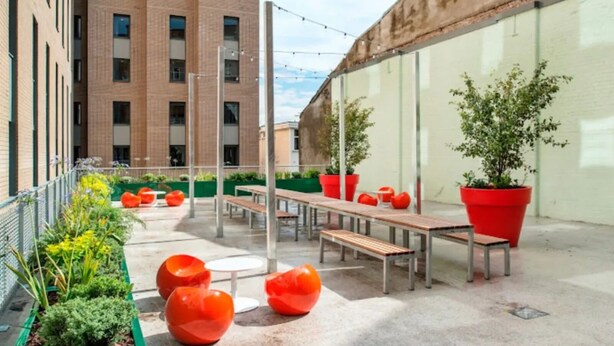 An outdoor patio area with benches, potted plants, and a view of a brick building. - Student Only Ablett House (Liverpool)