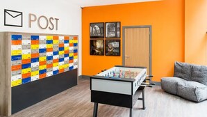 A room with a foosball table, a sofa, and a wall with mailboxes. - Student Only Ablett House (Liverpool)