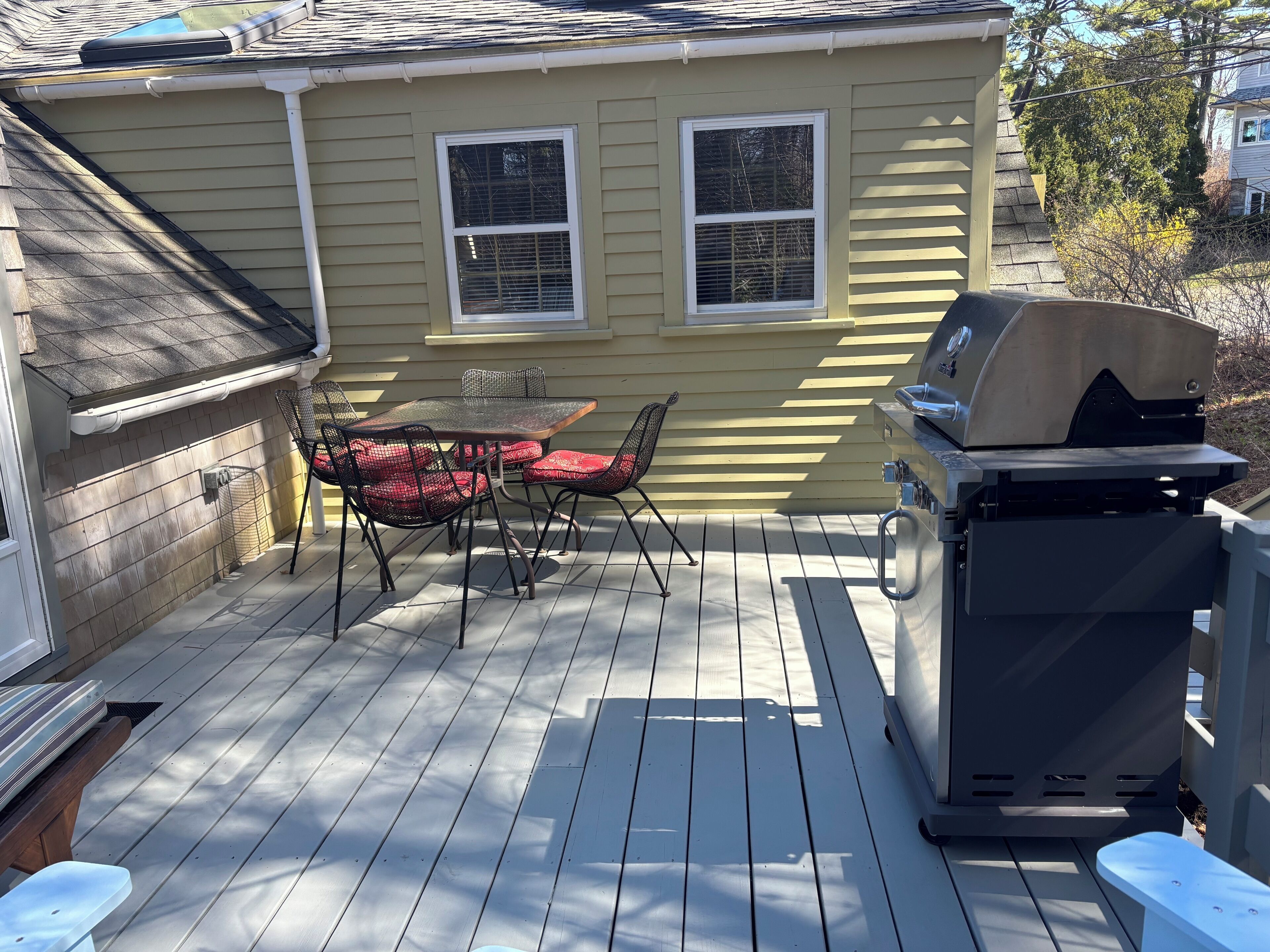 Een terras met een barbecue en buitenmeubilair.