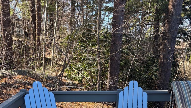 Puisesta laudasta rakennettu terassi, jossa on kaksi Adirondack-tyylistä tuolia ja penkki.