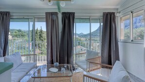 A balcony with a sofa, a chair, and a table with a glass. - Haut de Villa Helvétie - Welkeys (Toulon)