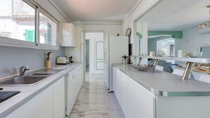 A modern kitchen with white cabinets, stainless steel countertops, and a marble floor. - Haut de Villa Helvétie - Welkeys (Toulon)