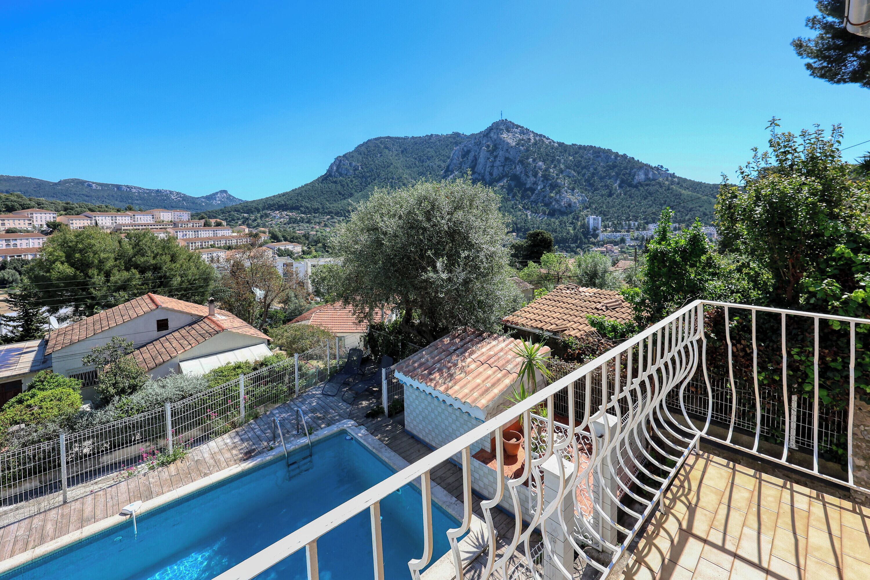 A pool area with a view of a mountain, surrounded by buildings and trees.