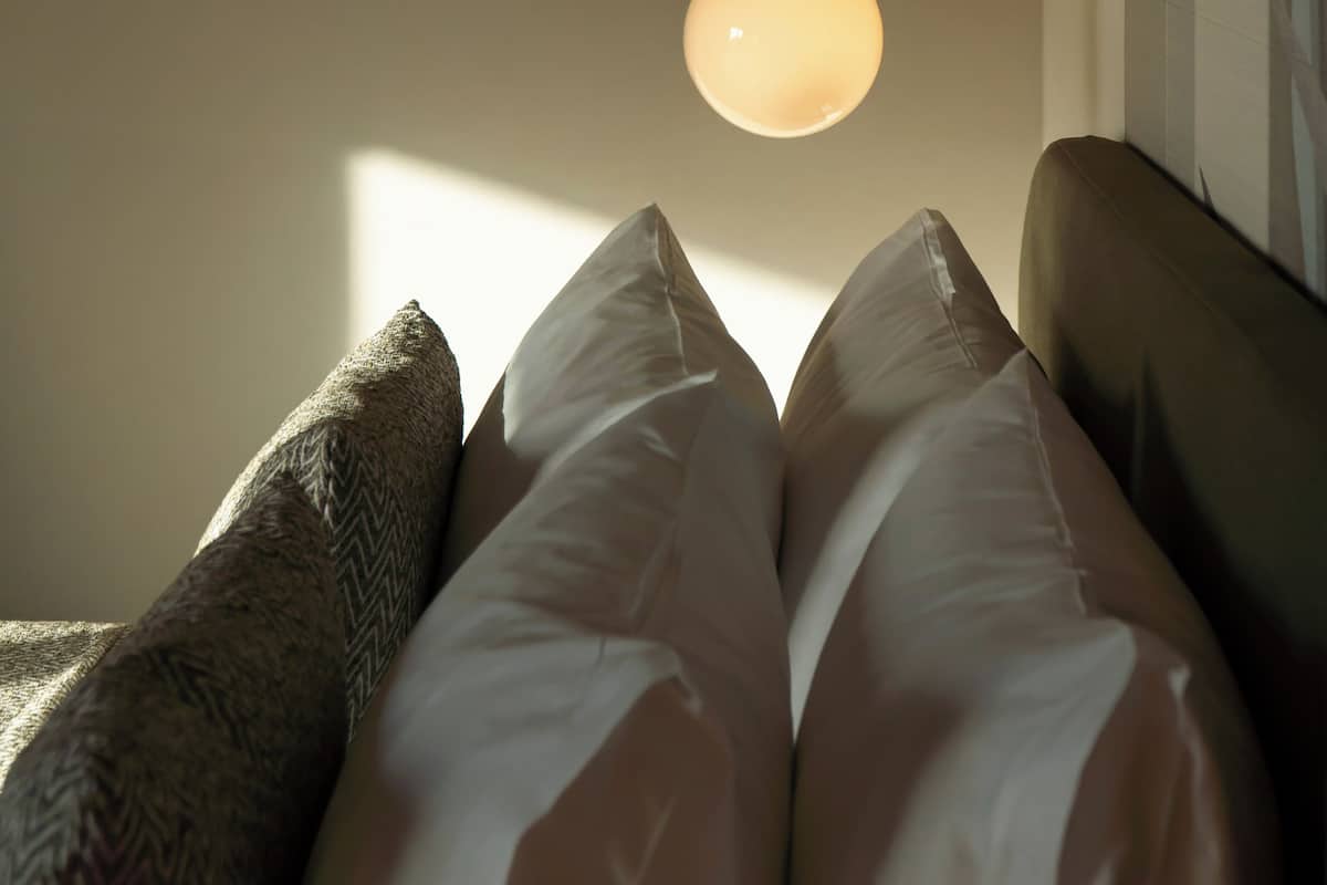 A bed with pillows and a hanging light fixture.