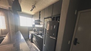 A kitchen with a granite countertop, stainless steel appliances, and a window providing natural light.