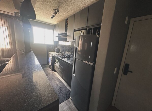 A kitchen with a granite countertop, stainless steel appliances, and a window providing natural light.