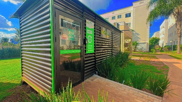 A modern building with a metal exterior, a glass door, and a green sign.