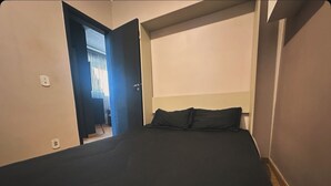 A bedroom with a bed, a headboard, and a door leading to another room.