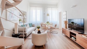 A modern living room with a spiral staircase, a sofa, a dining table with chairs, and a TV. - Luxury 2 Bedrooms 2 Bathrooms Penthouse, Elevator (Lucca)